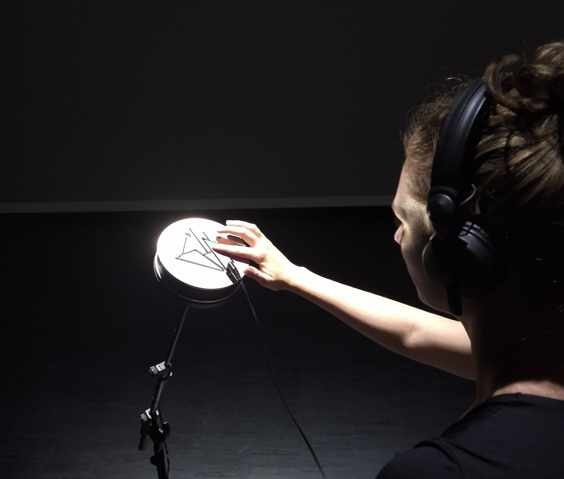 Une spectatrice équipée d'un casque appuie sur un bouton situé sur l'œuvre pour changer de piste audio